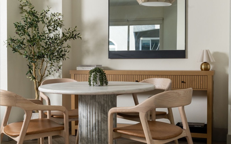 a dining room with a table, chairs and a mirror
